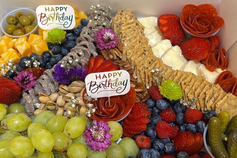 Birthday charcuterie spread with flowers, berries, crackers and chocolate