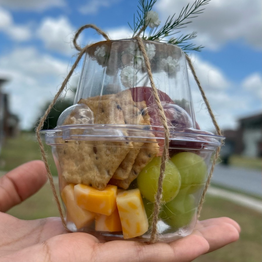 Single-serve charcuterie cup with cheese, grapes and crackers tied with twine
