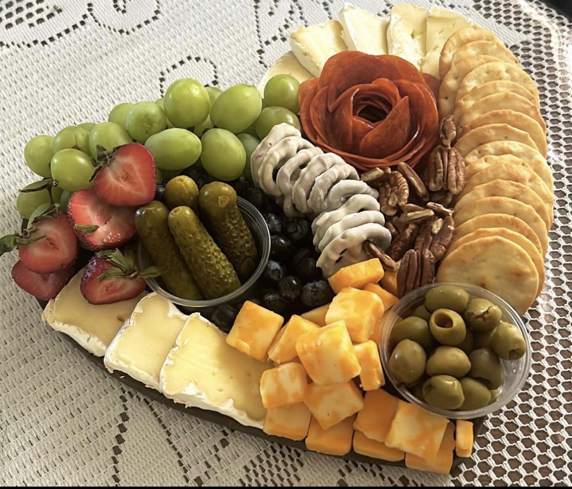 Heart-shaped charcuterie board with pepperoni rose, grapes and brie