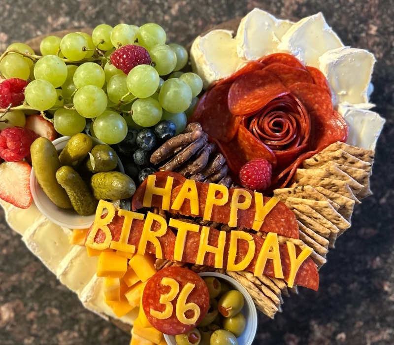 Heart charcuterie board spelling Happy Birthday in cheese and pepperoni